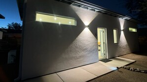 A modern house with a light-colored exterior, a visible door, and a small window. - Modern Studio Home SolMod # 1 (Tucson)