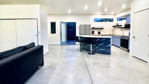 A modern kitchen with a central island, built-in appliances, and a seating area with a sofa. - Modern Studio Home SolMod # 1 (Tucson)
