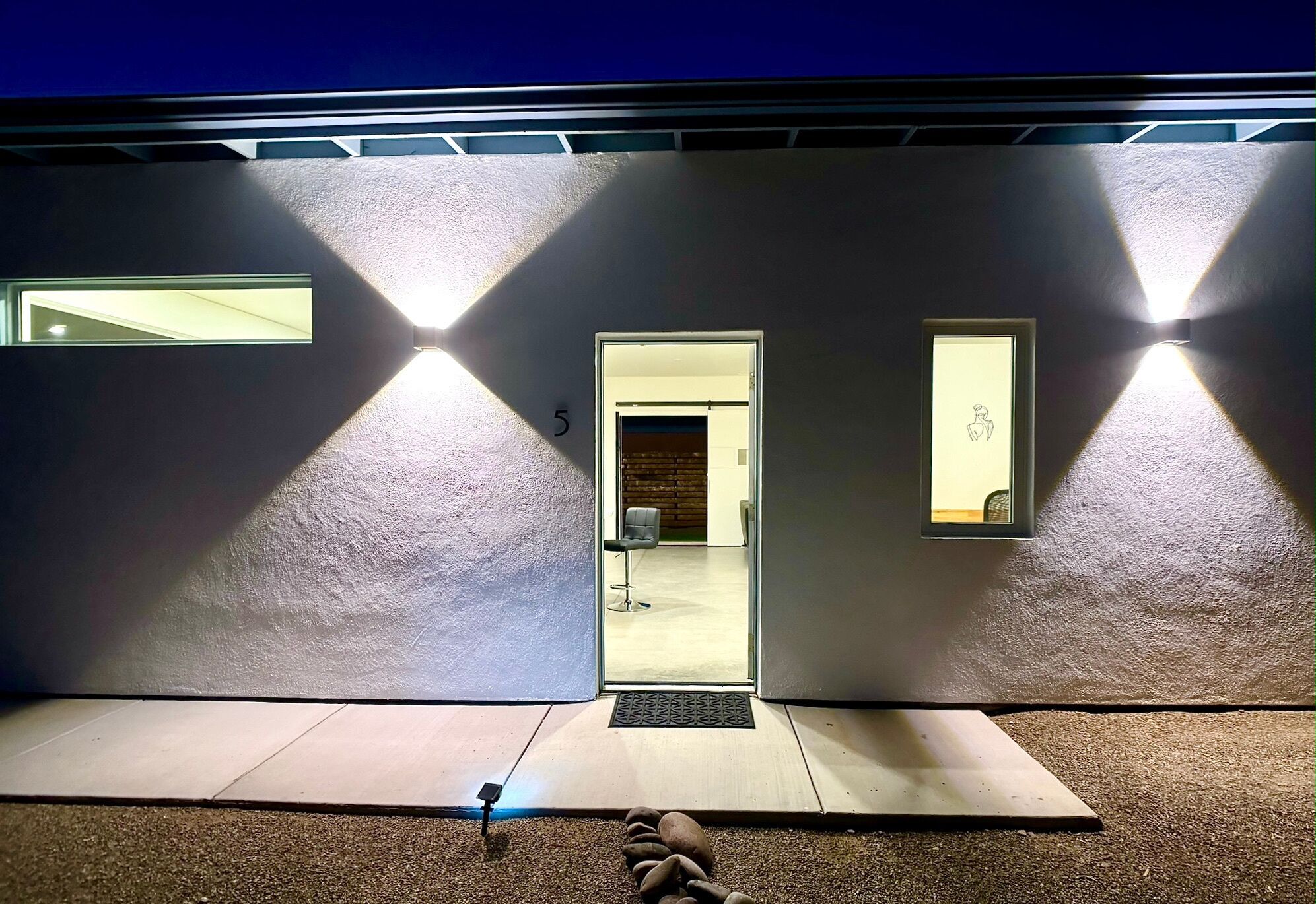 A modern building entrance with a door marked '5', a small window, and a wall-mounted light fixture.