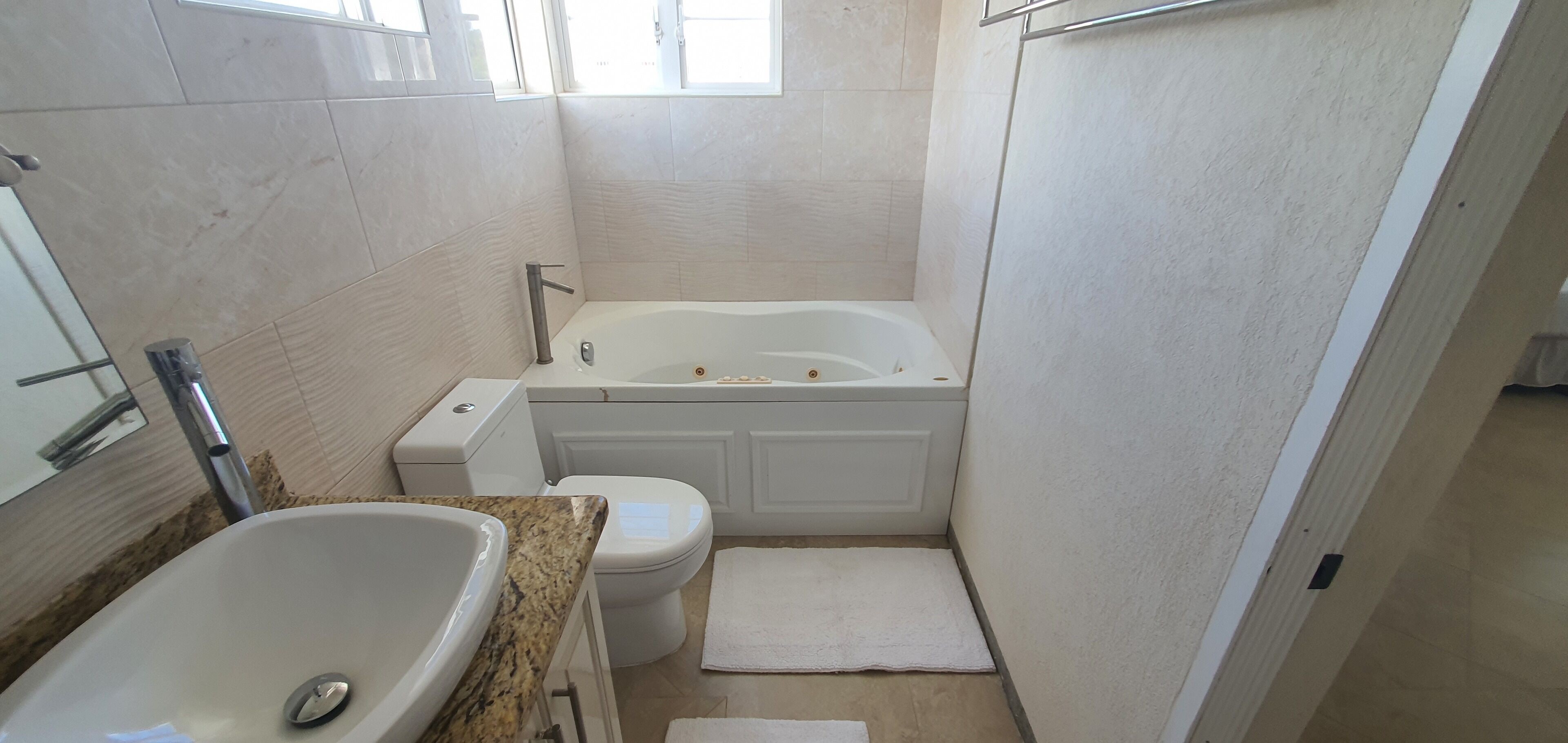 Un baño pequeño y moderno con bañera, inodoro y lavabo.