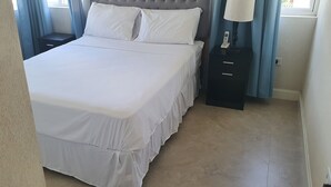 A neatly made bed with white linens, a headboard, and two bedside tables with a lamp on one. - Infinity Townhomes, Charming 3-bedroom, 3.5 bathroom townhouse, AC, fitness room (Bagatelle Terrace)