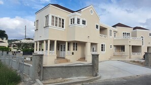 A multi-story residential building with a beige facade, white trim, and balconies. - Infinity Townhomes, Charming 3-bedroom, 3.5 bathroom townhouse, AC, fitness room (Bagatelle Terrace)