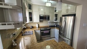 A kitchen with white cabinets, stainless steel appliances, granite countertops, and a built-in oven. - Infinity Townhomes, Charming 3-bedroom, 3.5 bathroom townhouse, AC, fitness room (Bagatelle Terrace)