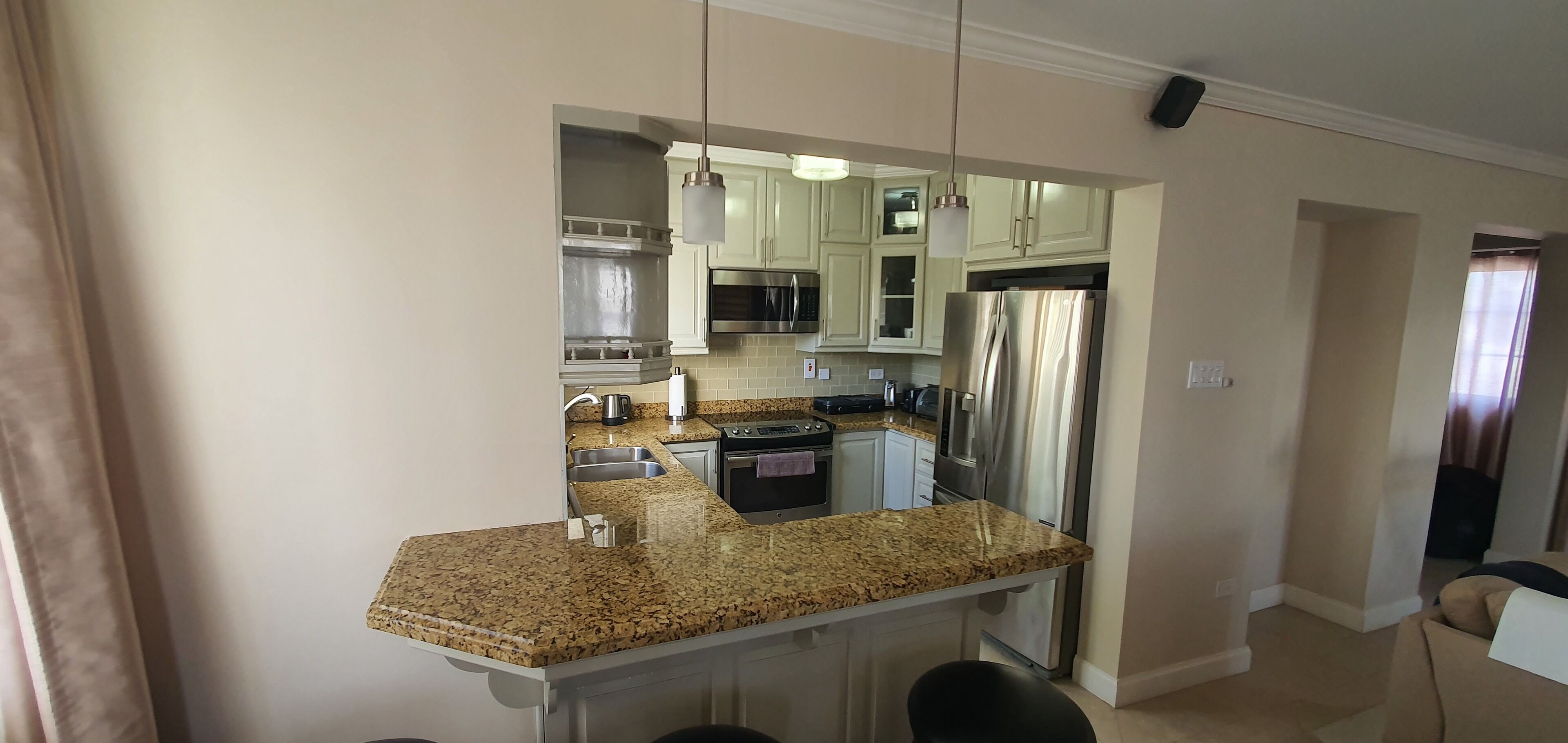 Una cocina moderna con encimeras de granito, electrodomésticos de acero inoxidable y armarios blancos.