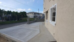 A building with a beige exterior, a white window, and a paved sidewalk. - Infinity Townhomes, Charming 3-bedroom, 3.5 bathroom townhouse, AC, fitness room (Bagatelle Terrace)