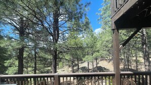 A wooden deck with a railing overlooking a forested area. - Flagstaff Family Retreat — Game Room, Gym, Fire Pit & Forest Fun! (Flagstaff)