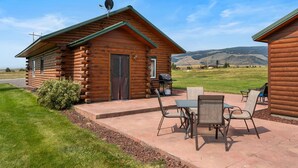 A log cabin with a patio area featuring outdoor furniture and a grill.