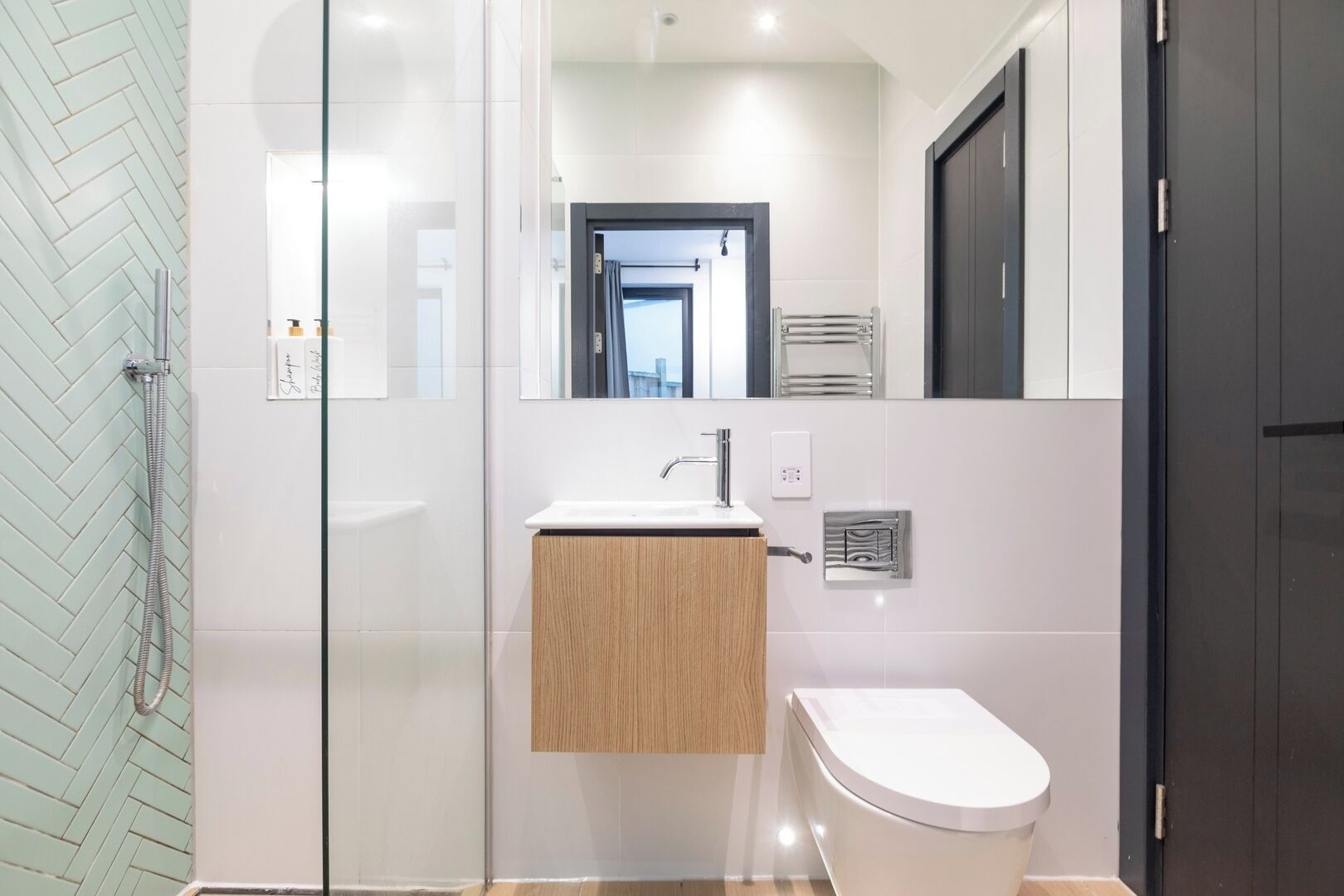 A modern bathroom with a glass shower enclosure, a wooden vanity, and a white toilet.