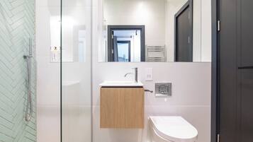 A modern bathroom with a glass shower enclosure, a wooden vanity, and a white toilet.