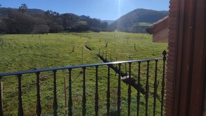 Un balcón con vistas a un campo verde y colinas.