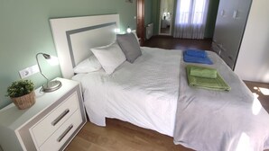 Un dormitorio con cama, mesita de noche, lámpara y armario.
