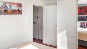 A room with a bed, a door, and a cityscape painting on the wall. - Beautiful view Apt
Near Canary Wharf (London)