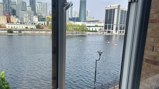 A view of a river with boats, a city skyline, and a lamp post. - Beautiful view Apt
Near Canary Wharf (London)