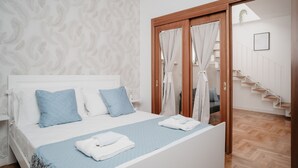 Une chambre à coucher avec un lit, des murs blancs, une porte en bois et un escalier.