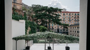 Une terrasse sur le toit avec des sièges extérieurs, une pergola recouverte de verdure et une vue sur les bâtiments environnants.
