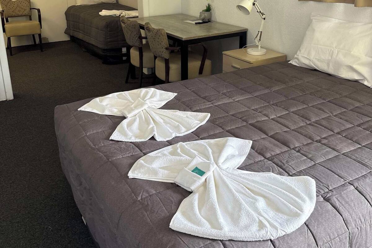 Et hotelværelse med en seng, et skrivebord, en stol, et bord og en aircondition.