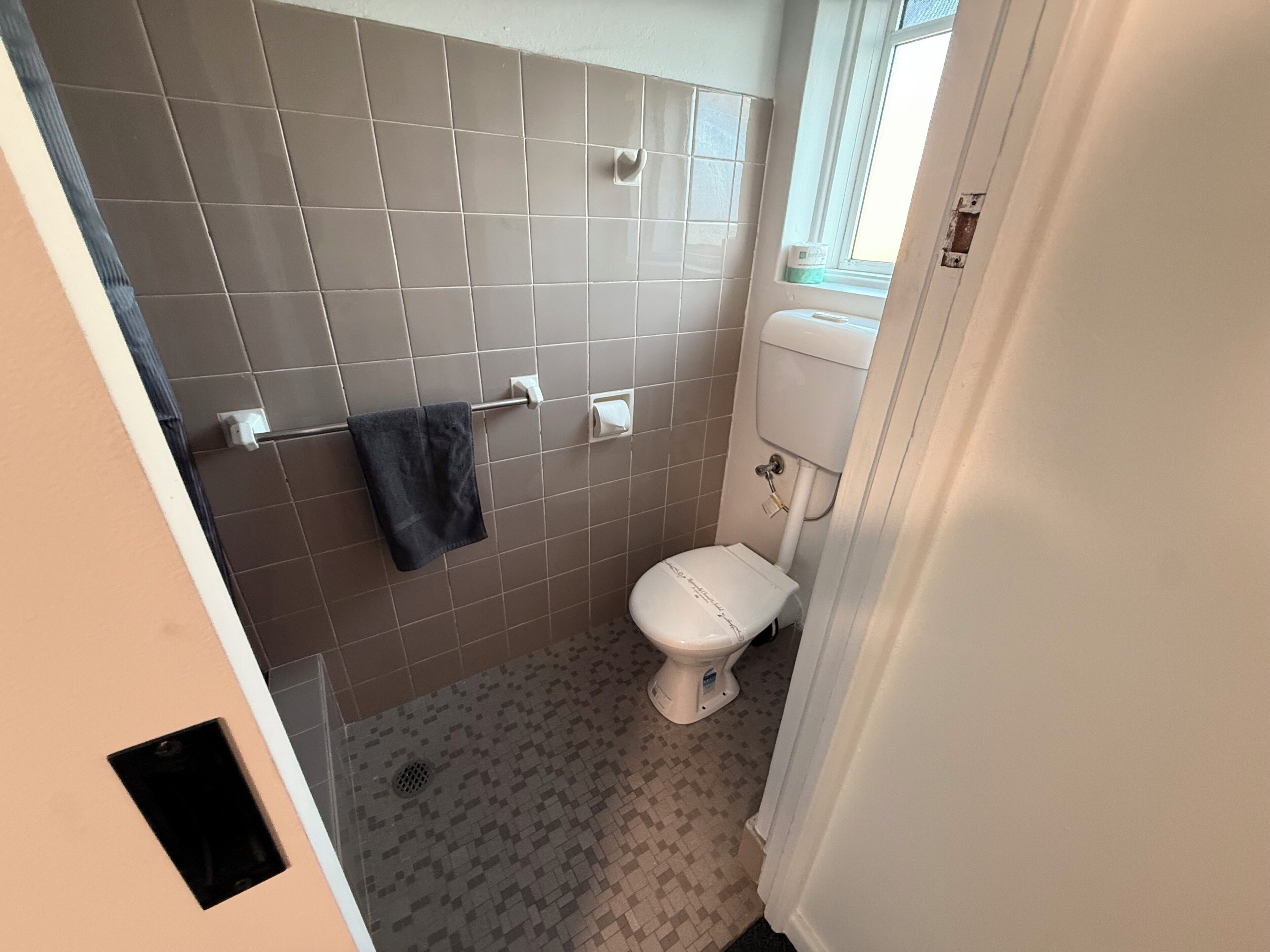 Un bagno con il water, un portasciugamani e una finestra.