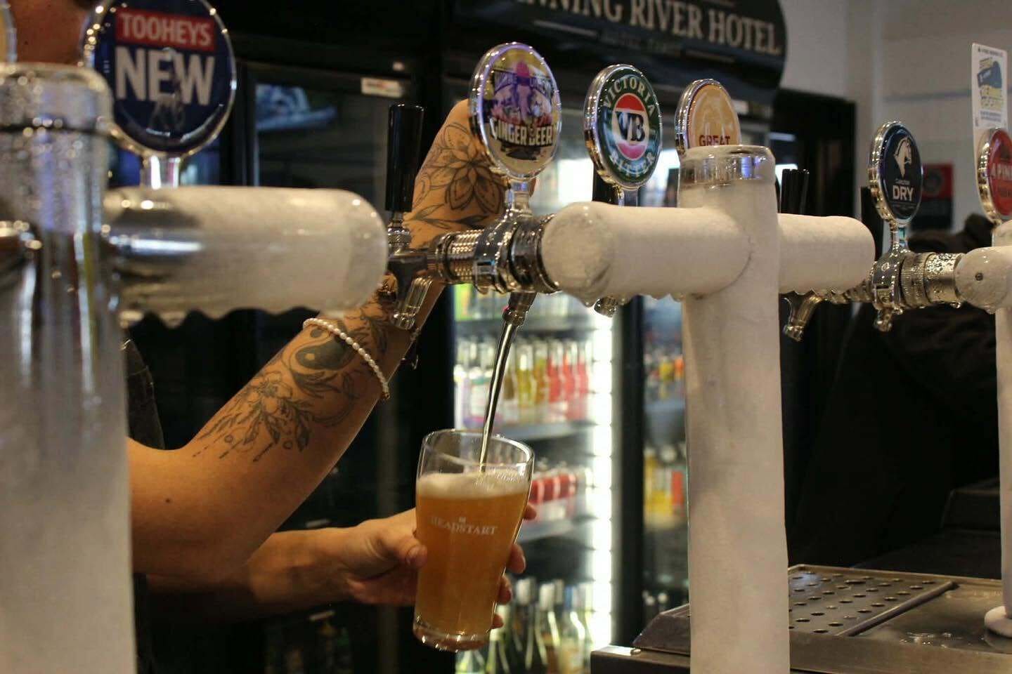 Un cantinero sirviendo cerveza de una grifo en un vaso.