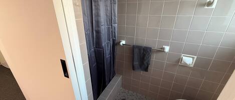 Un baño con cortina de ducha, toallero, inodoro y paredes de azulejos.