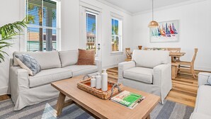 Een moderne woonkamer met twee banken, een salontafel en een eethoek met houten meubels.