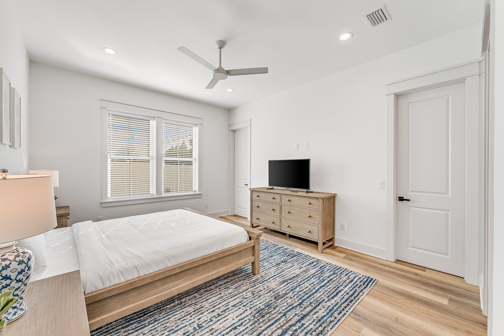 Quarto com cama, cômoda, televisão e ventilador de teto.