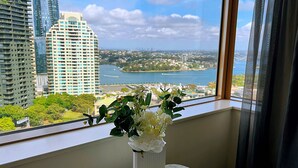 A view from a window with a vase of white flowers on a marble table. - Fancy home with water view in the rocks (The Rocks)