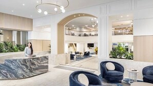 A hotel lobby with a reception desk, seating area, and a second-floor balcony with a view. - Fancy home with water view in the rocks (The Rocks)