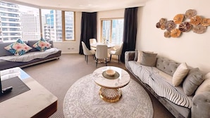 A modern living room with a sofa, a round coffee table, and a dining area with a table and chairs. - Fancy home with water view in the rocks (The Rocks)