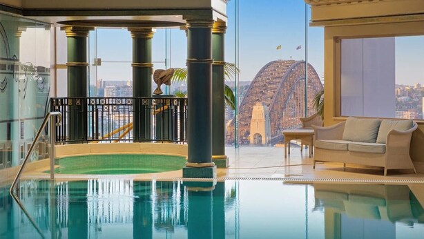 A luxurious indoor pool area with a view of a bridge and cityscape. - Fancy home with water view in the rocks (The Rocks)
