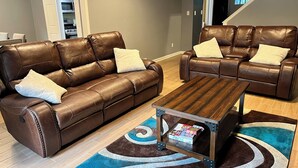 A living room with two brown leather sofas, a wooden coffee table, and a blue and brown patterned rug. - Spacious 4-bedroom house in charming Memphis with AC, WiFi (Memphis)
