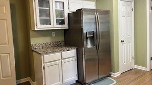 A kitchen with a stainless steel refrigerator, white cabinets, and a granite countertop. - Spacious 4-bedroom house in charming Memphis with AC, WiFi (Memphis)