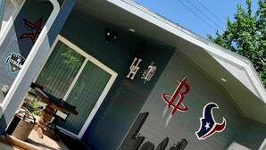 A house with a garage door featuring the Houston Astros logo. - Charming 2-bedroom house with AC and WiFi in cool Houston (Houston)