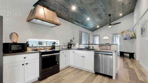 A modern kitchen with white cabinets, a wooden ceiling, and a built-in dishwasher. - Charming 2-bedroom house with AC and WiFi in cool Houston (Houston)