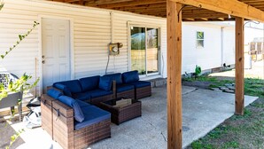 Portico esterno coperto con un divano componibile, un tavolino e una porta che dà su una casa.