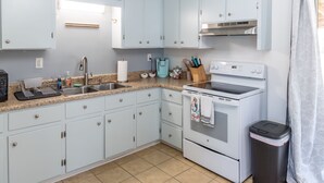Cucina con mobili azzurri, lavello in acciaio inossidabile, macchina da caffè e piano cottura.