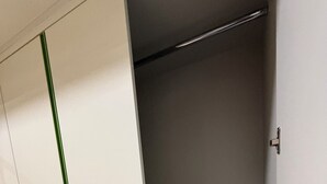 A room with a wardrobe, a metal shelf, and a door with a handle.