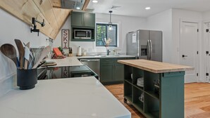A modern kitchen with a wooden ceiling, a built-in microwave, a stainless steel refrigerator, and a wooden island with a sink. - The Chalet - A Frame in the Overlook, close to Saddleback! (Rangeley)