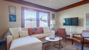 A living room with a sofa, armchairs, a coffee table, and a flat-screen TV.