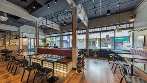 A spacious restaurant with wooden flooring, high ceilings, and large windows. - Upstairs at Ton Ton (Bangkok)