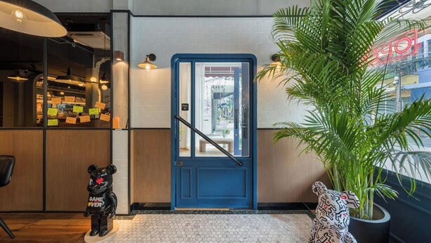 A hotel lobby with a blue door, a potted plant, and a bear statue. - Upstairs at Ton Ton (Bangkok)