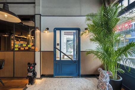A hotel lobby with a blue door, a potted plant, and a bear statue.