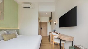 A hotel room with a bed, desk, chairs, a flat-screen TV, and an air conditioning unit. - Upstairs at Ton Ton (Bangkok)