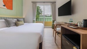 A hotel room with a bed, a desk, a television, and a view of the outside. - Upstairs at Ton Ton (Bangkok)