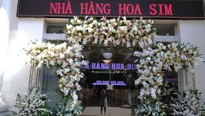 A hotel entrance with a large floral arch and signage reading "NHÀ HÀNG HOA SIM".