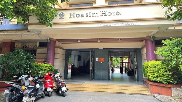 The entrance to Hoa Sin Hotel with a clear sign, a covered entrance, and a few parked scooters.