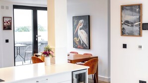 A modern dining area with a wooden table and chairs, a vase of flowers, and artwork on the walls.