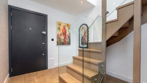 A modern staircase with glass railings, wooden steps, and a black door.