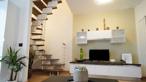 Una sala de estar moderna con una escalera, un televisor de pantalla plana y una decoración minimalista.