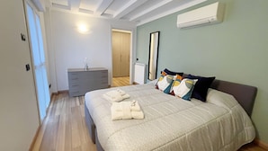 Un dormitorio con cama, cómoda, espejo y unidad de aire acondicionado.