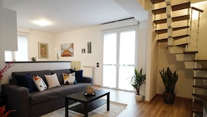 Una sala de estar moderna con un sofá gris, una mesa de centro negra y una escalera de caracol.